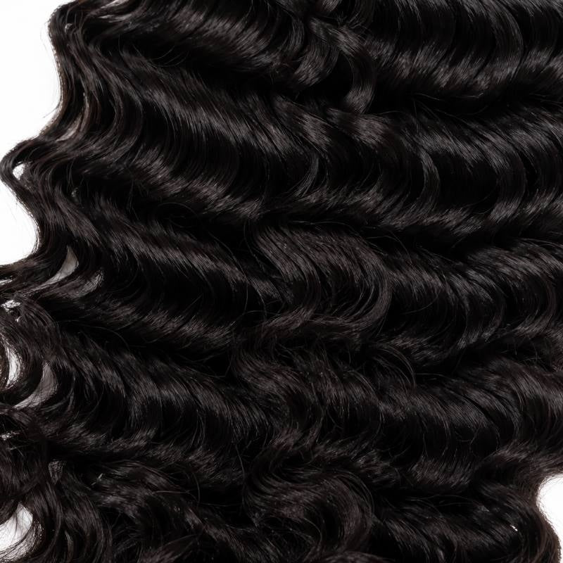 Macro view of natural black curly sew-in hair extensions showing the defined curl pattern running across the frame