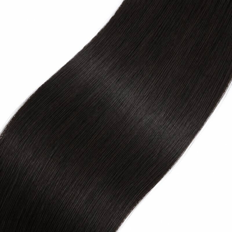 Macro view of natural black straight sew-in hair extensions running diagonally with a soft band of light along the strands