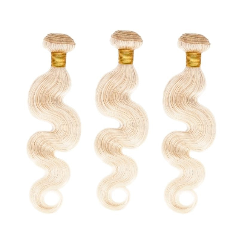 Three bundles of blonde body wave sew-in hair extensions standing side by side on a white background with gold thread wrapped wefts