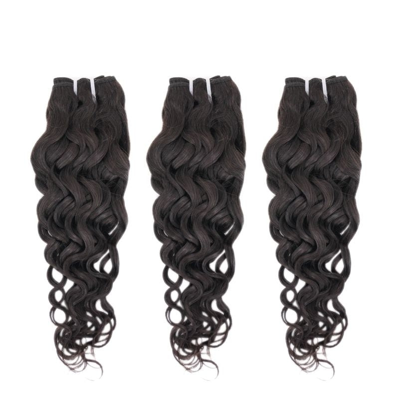Three wefts of natural black sew-in hair extensions hanging on a white background with a defined wave pattern loosening into curls at the ends