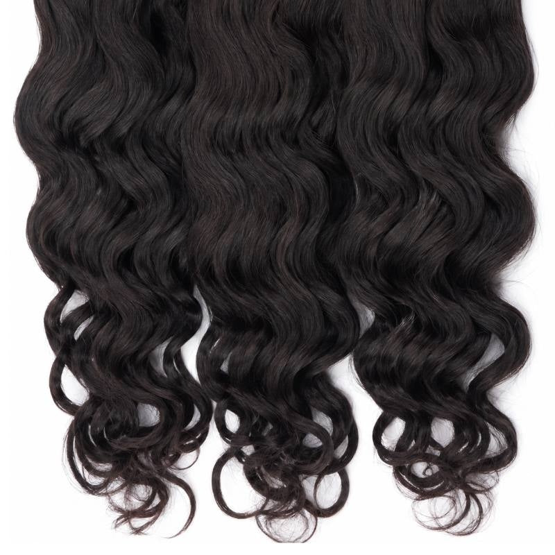 Close-up of the ends of three bundles of natural black sew-in hair extensions where the waves loosen into open curls