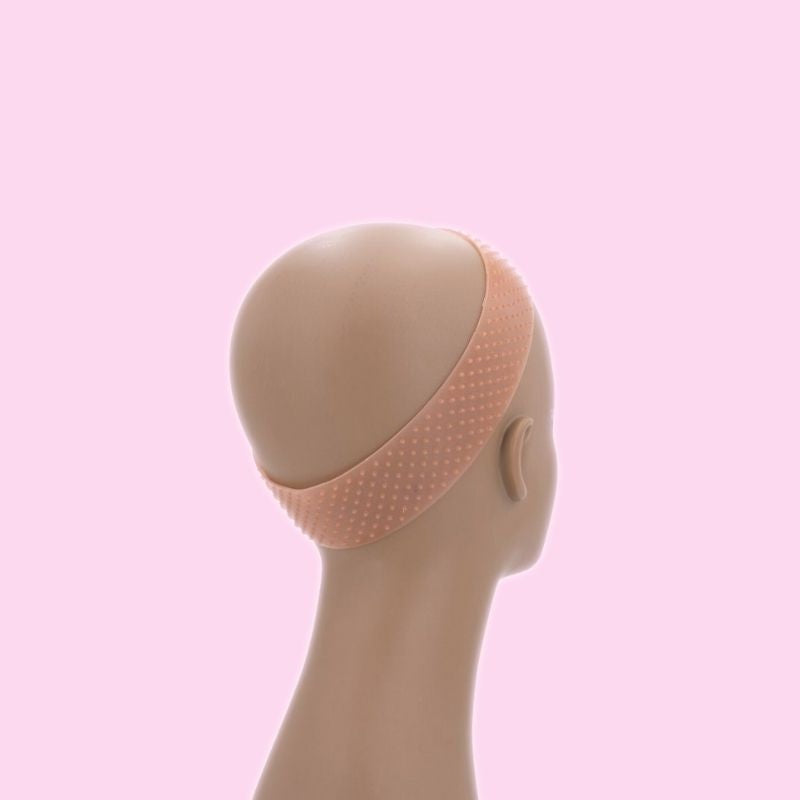 Beige silicone wig grip band fitted around a bald mannequin head on a pink backdrop, used to hold wigs and hair extensions in place