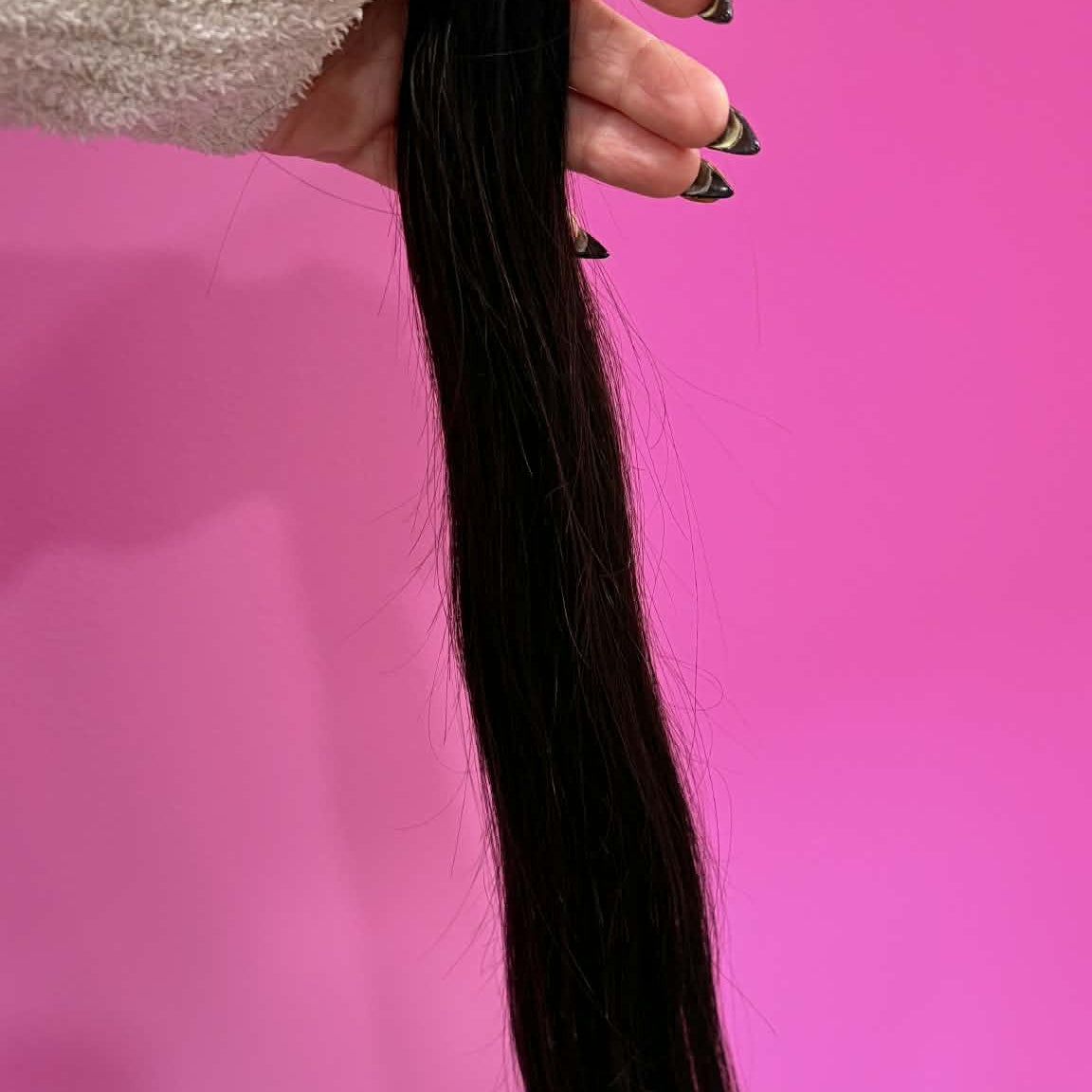 Hand holding 20 inch straight natural black tape-in hair extension showing full hair length from tape tab to tips