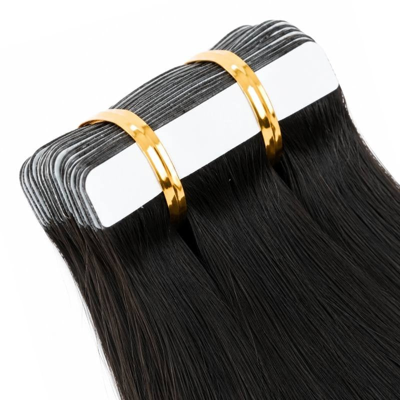 Angled close-up of the adhesive tape tabs on natural black straight tape-in hair extensions held in a banded stack